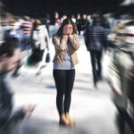 Panic attack in public place. Woman having panic disorder in city. Psychology, solitude, fear or mental health problems concept. Depressed sad person surrounded by people walking in busy street.